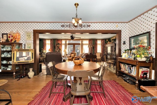 dining area with crown molding, ceiling fan with notable chandelier, and hardwood / wood-style floors