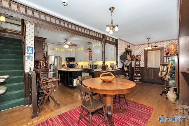 dining room featuring crown molding, wood-type flooring, and ceiling fan with notable chandelier