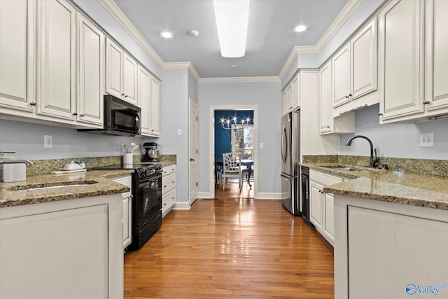 kitchen with light stone counters, crown molding, light hardwood / wood-style floors, white cabinets, and black appliances