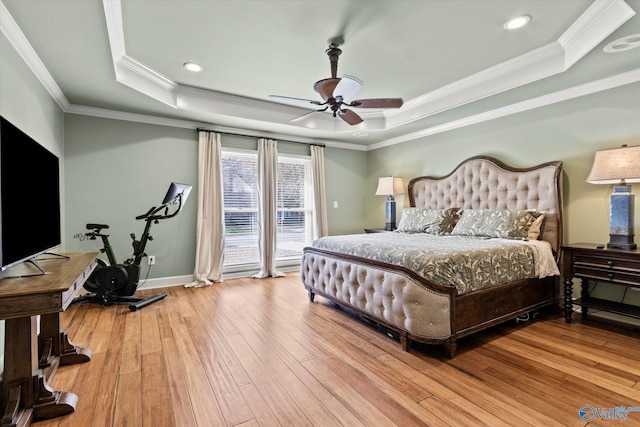 bedroom featuring ceiling fan, crown molding, a tray ceiling, and light hardwood / wood-style flooring