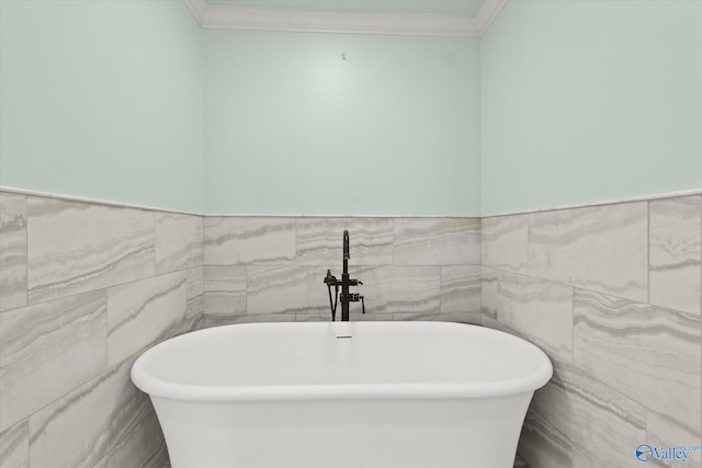 bathroom with a bathtub, crown molding, and tile walls