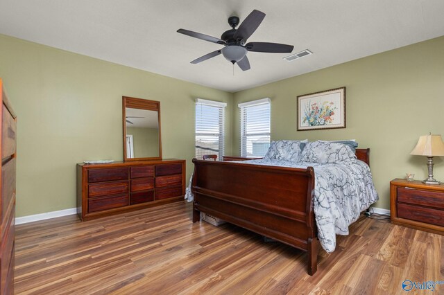 bedroom featuring visible vents, baseboards, a ceiling fan, and wood finished floors