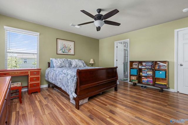 bedroom featuring wood finished floors, ceiling fan, baseboards, and visible vents