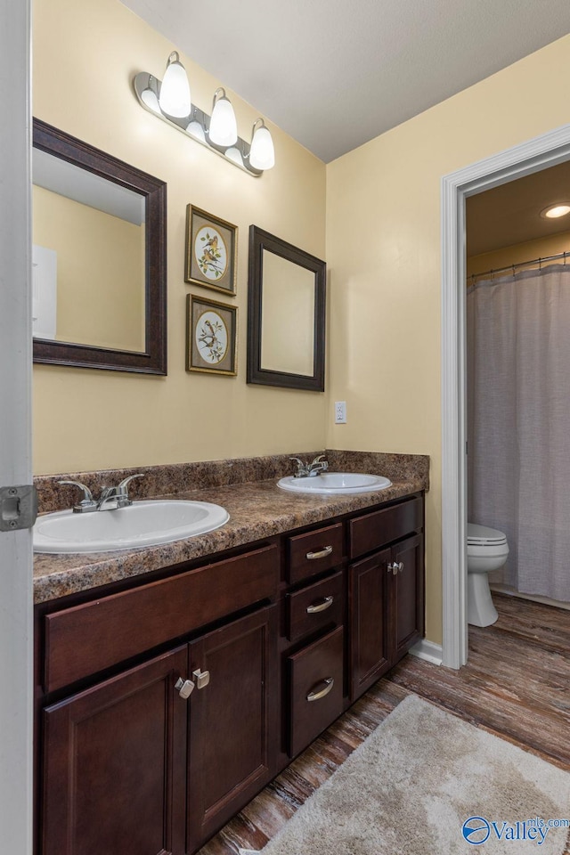 bathroom with double vanity, a sink, and toilet