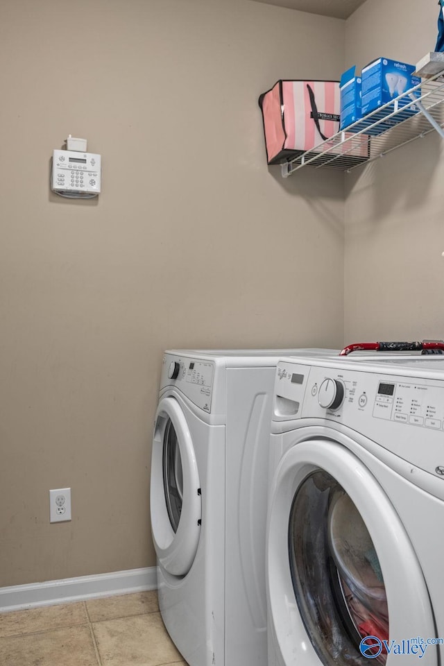laundry area featuring separate washer and dryer, laundry area, baseboards, and light tile patterned flooring
