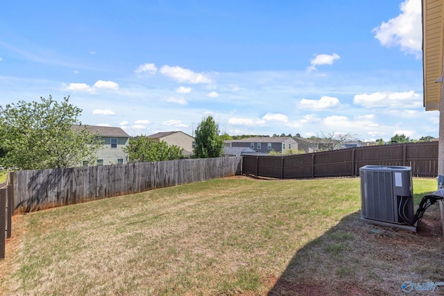 view of yard featuring central air condition unit, a fenced backyard, and a residential view