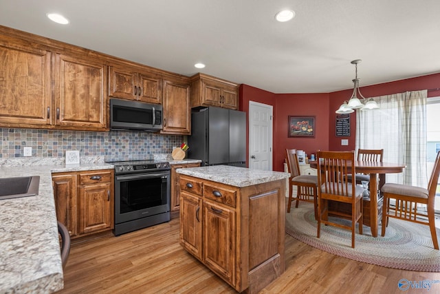 kitchen with light wood-style floors, brown cabinets, and appliances with stainless steel finishes