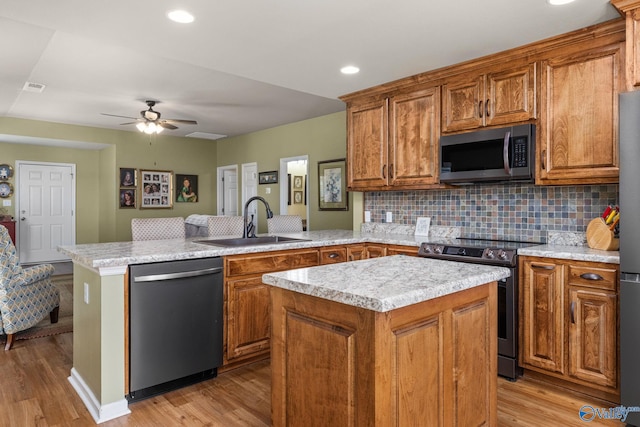 kitchen featuring a sink, light countertops, a peninsula, and stainless steel appliances