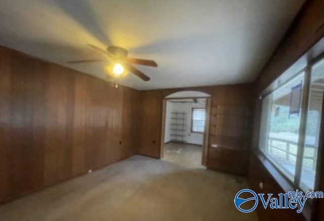 spare room featuring ceiling fan, light colored carpet, and wooden walls