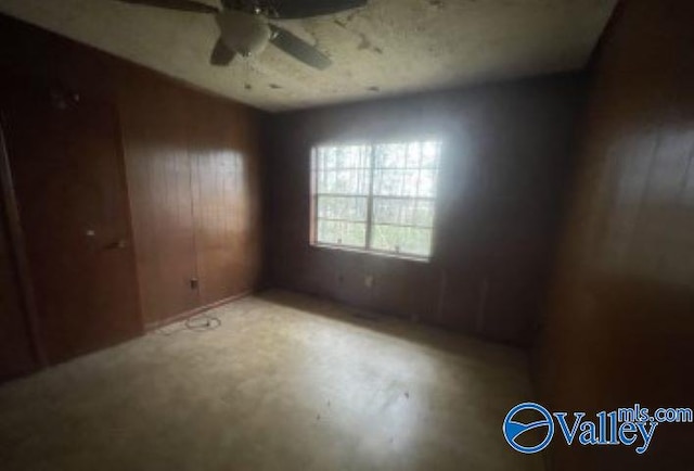 spare room with wood walls and ceiling fan