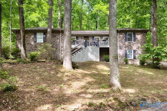 view of front of property with stairway, a wooden deck, and brick siding