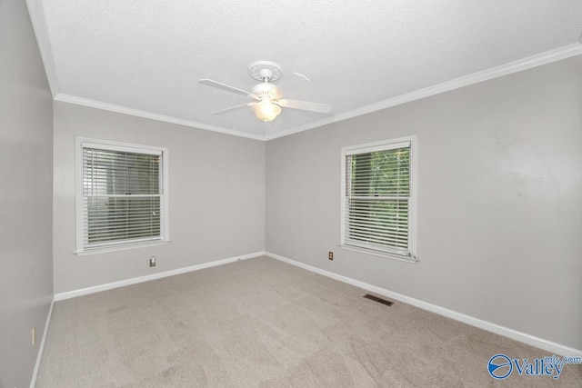 spare room featuring ornamental molding, visible vents, carpet floors, a ceiling fan, and baseboards