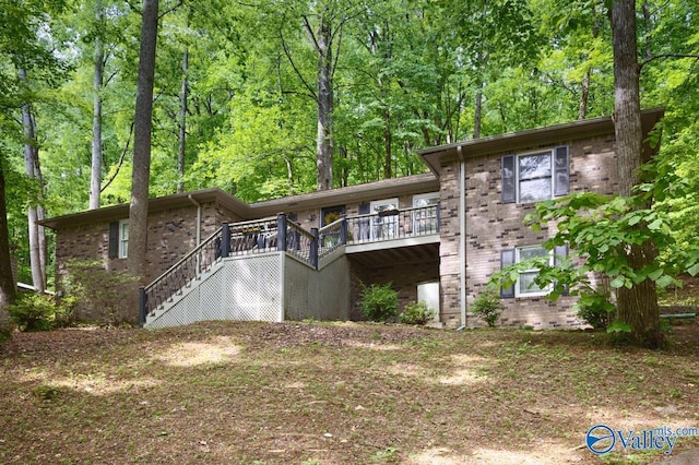 back of property featuring stairway, a wooden deck, and brick siding