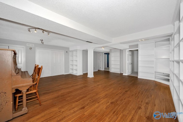 unfurnished living room featuring wood finished floors, a textured ceiling, visible vents, built in features, and baseboards