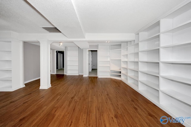 below grade area featuring a textured ceiling, wood finished floors, baseboards, and built in shelves