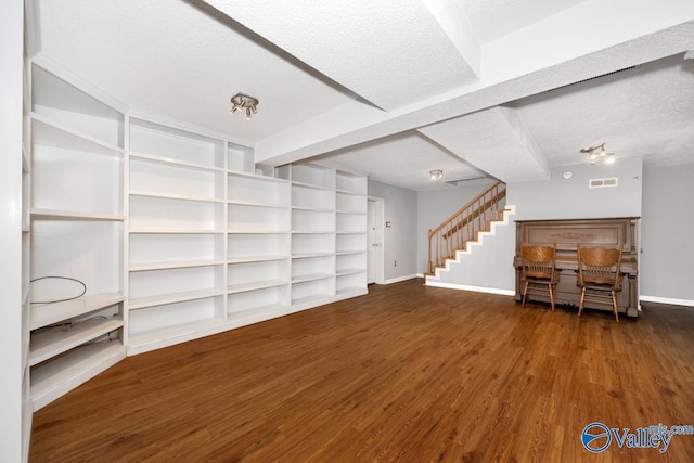interior space featuring a textured ceiling, baseboards, visible vents, stairs, and wood finished floors