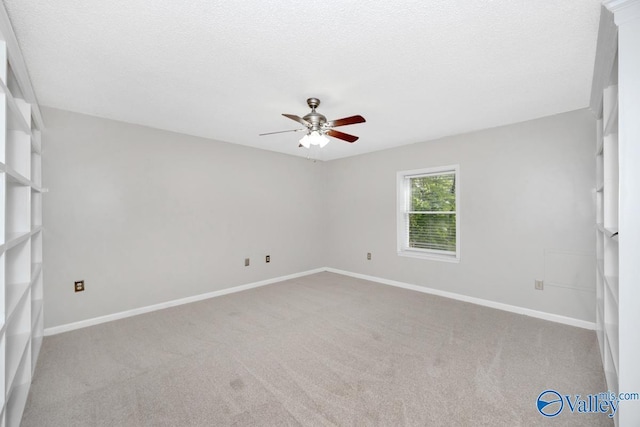 carpeted spare room featuring a textured ceiling, baseboards, and a ceiling fan