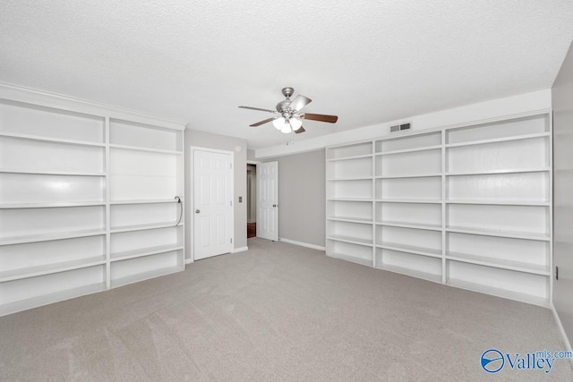 unfurnished bedroom featuring a textured ceiling, carpet, visible vents, ceiling fan, and baseboards