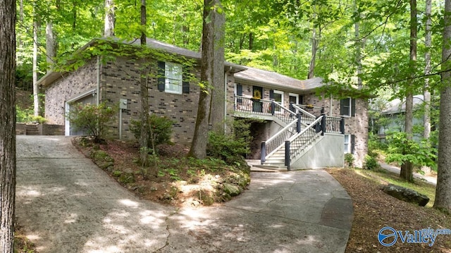 view of front of property with covered porch, stairs, brick siding, and driveway