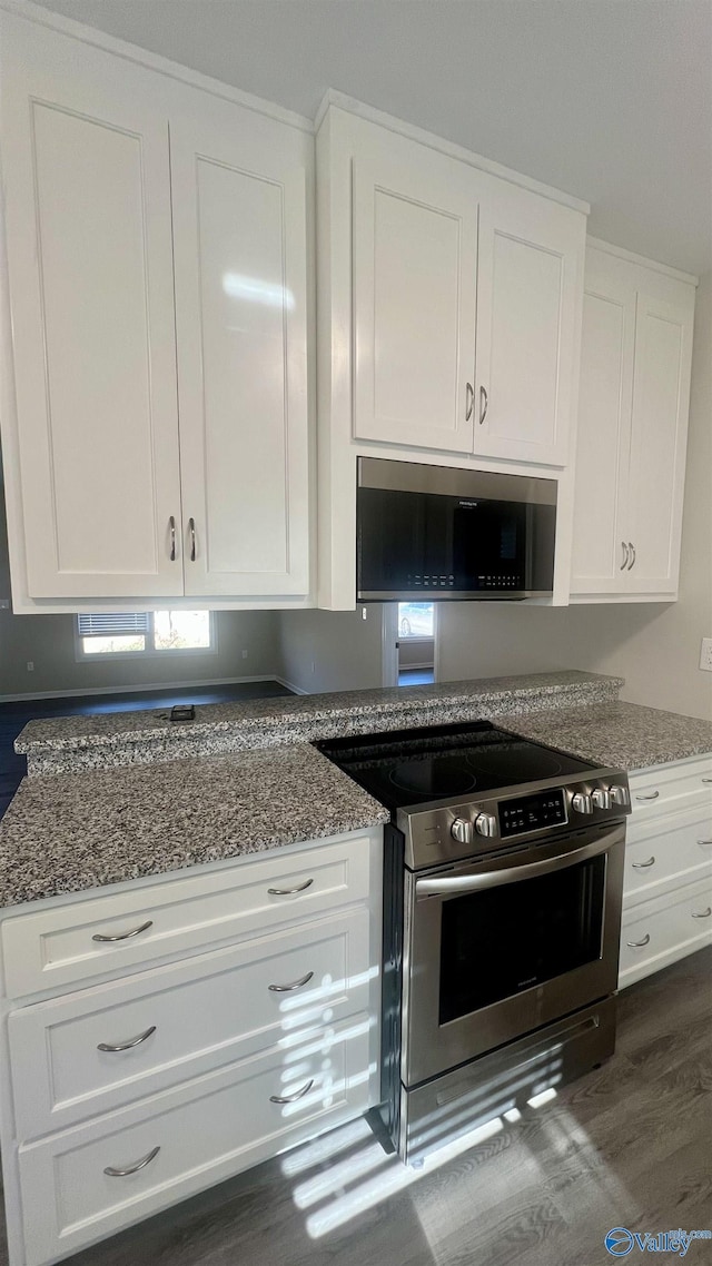 kitchen featuring stainless steel appliances, dark stone counters, white cabinetry, and dark wood finished floors