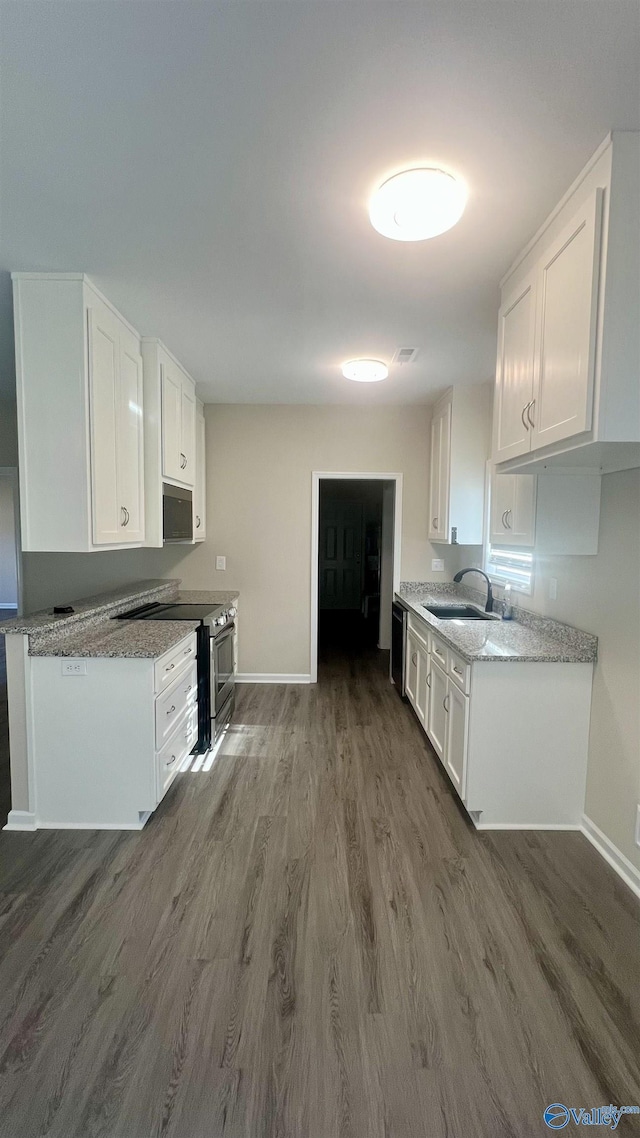 kitchen with dark wood finished floors, stainless steel appliances, white cabinetry, a sink, and baseboards