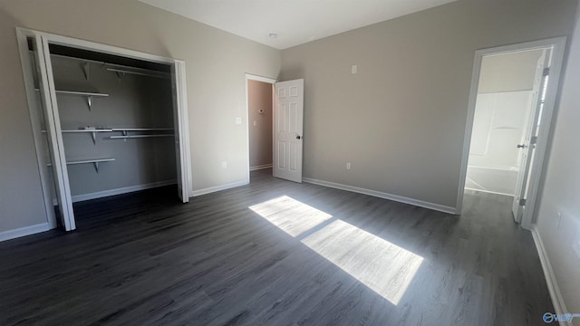 unfurnished bedroom featuring a closet, dark wood finished floors, and baseboards