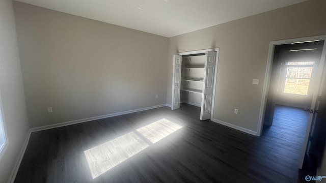 unfurnished bedroom featuring a closet, dark wood finished floors, and baseboards