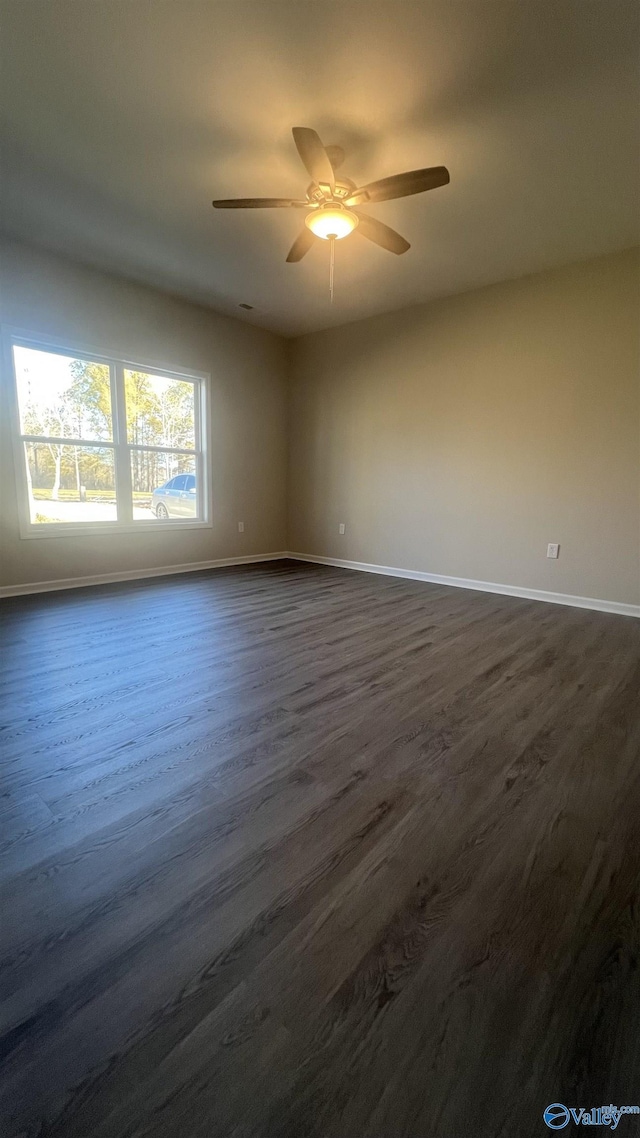 spare room with a ceiling fan, dark wood finished floors, and baseboards