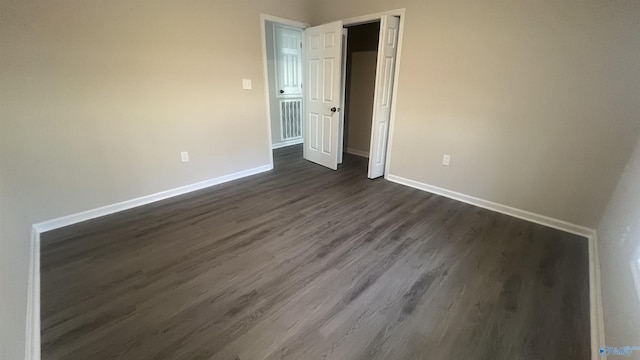 unfurnished bedroom with baseboards and dark wood-style flooring