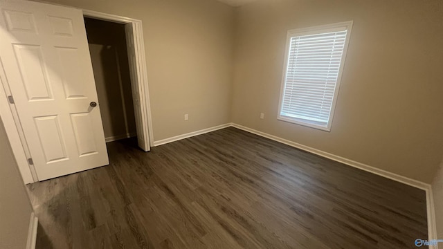 unfurnished bedroom with dark wood finished floors and baseboards