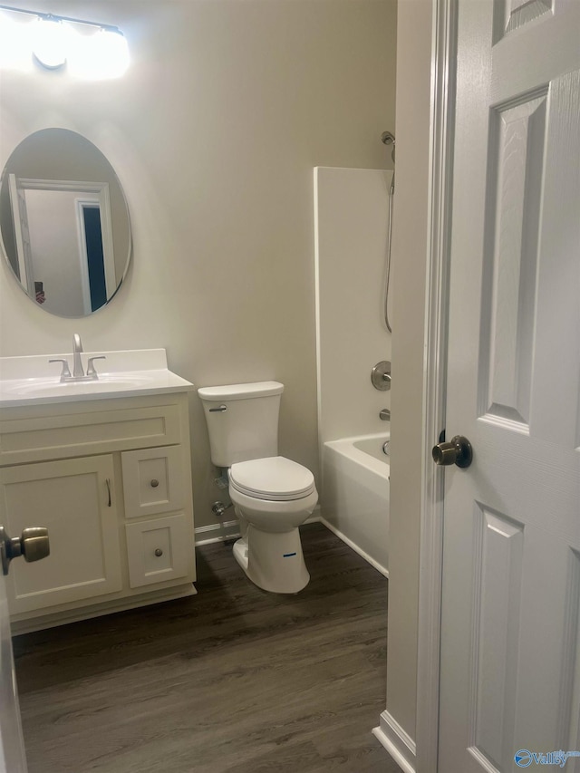 bathroom with baseboards, toilet, wood finished floors, tub / shower combination, and vanity