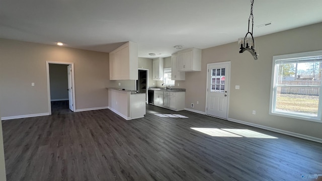 kitchen featuring visible vents, white cabinets, open floor plan, a peninsula, and a sink