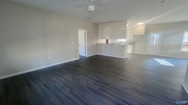 unfurnished living room with ceiling fan, dark wood-style flooring, a sink, and baseboards