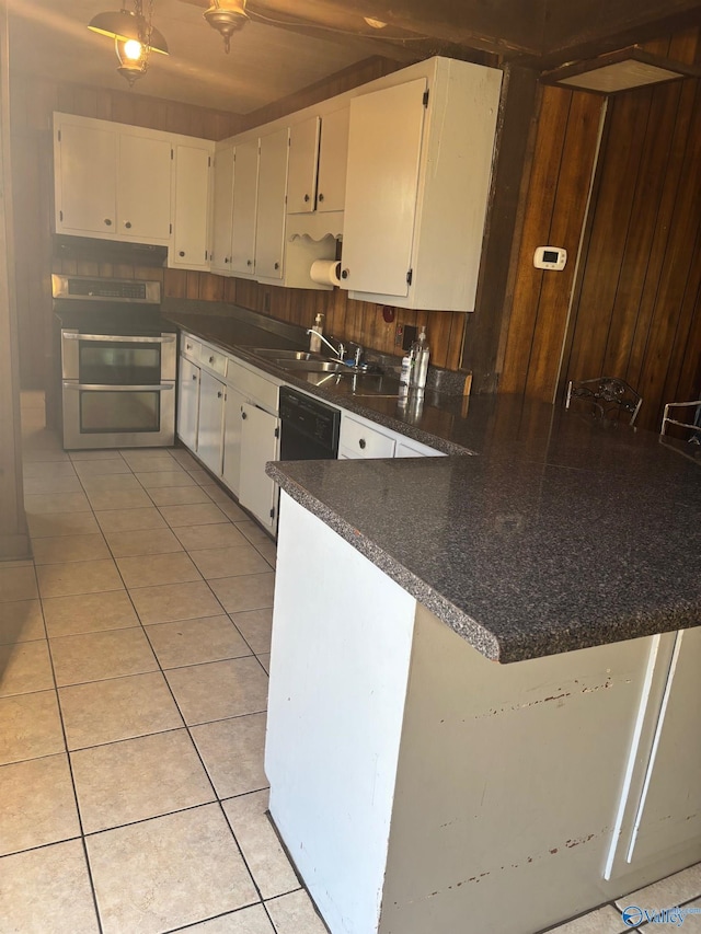 kitchen featuring black dishwasher, light tile patterned floors, dark countertops, white cabinetry, and a peninsula