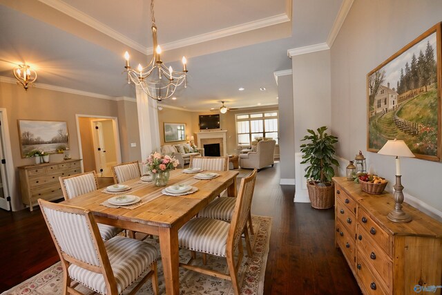 dining space with ceiling fan with notable chandelier, crown molding, dark wood-style floors, and a fireplace