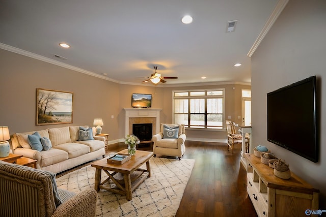 living area featuring dark wood-type flooring, ornamental molding, a tiled fireplace, recessed lighting, and baseboards