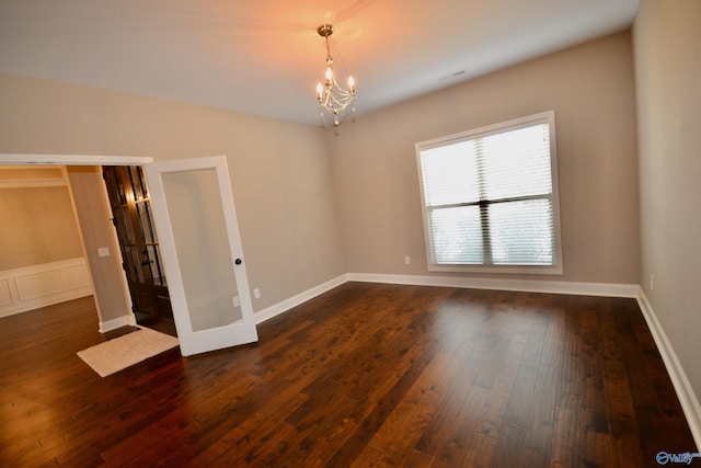 spare room featuring french doors, baseboards, an inviting chandelier, and dark wood finished floors