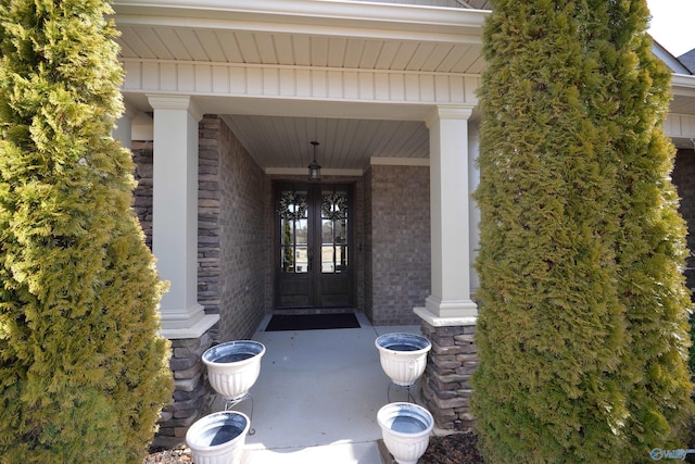 view of exterior entry with french doors, stone siding, and brick siding