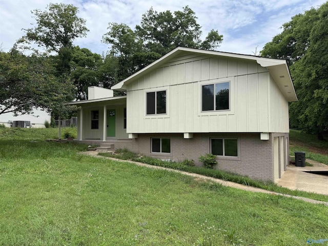 1605 Phillips Dr, Scottsboro, AL 35769 - split level home featuring brick siding, a front yard, covered porch, a chimney, and board and batten siding