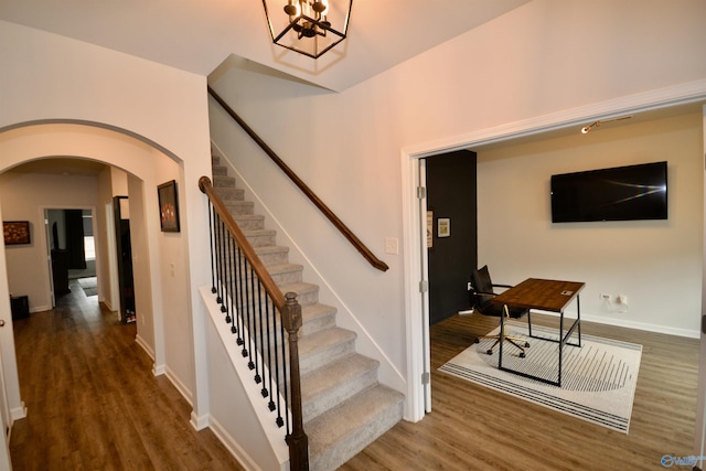 stairs with wood-type flooring and a chandelier