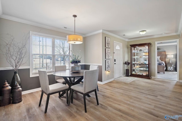 dining room with baseboards, visible vents, ornamental molding, and wood finished floors