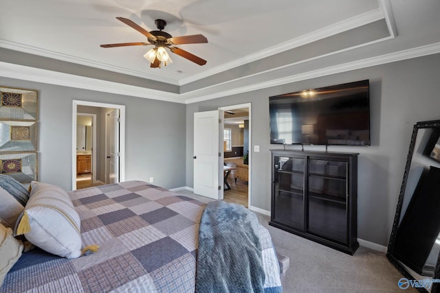 carpeted bedroom with connected bathroom, a ceiling fan, baseboards, a tray ceiling, and crown molding