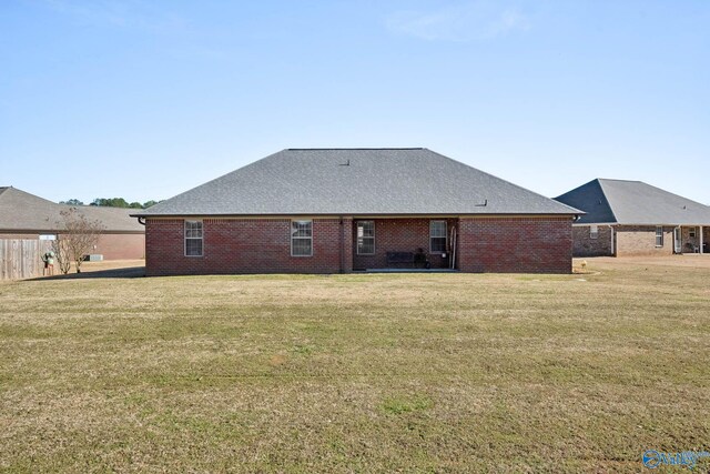 back of property with roof with shingles, a lawn, and brick siding