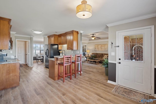 kitchen featuring open floor plan, a breakfast bar, stainless steel microwave, and brown cabinets
