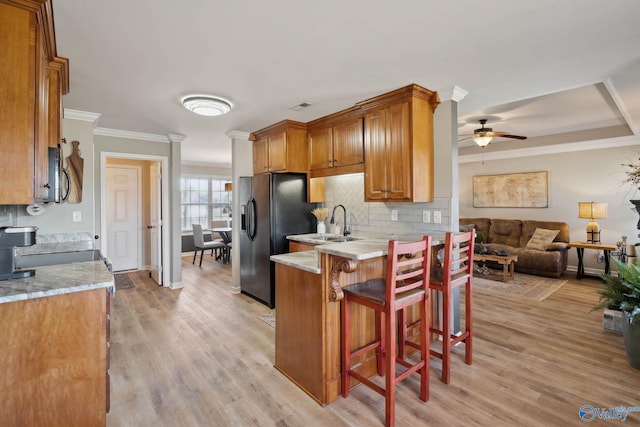 kitchen with brown cabinetry, a kitchen bar, open floor plan, and crown molding