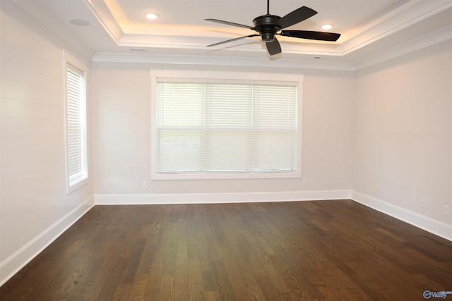 spare room with dark wood-type flooring, a tray ceiling, and ceiling fan