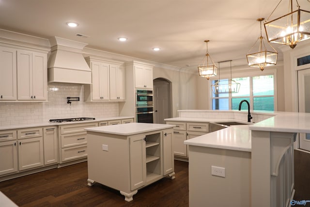 kitchen with sink, a kitchen island with sink, appliances with stainless steel finishes, backsplash, and dark wood-type flooring