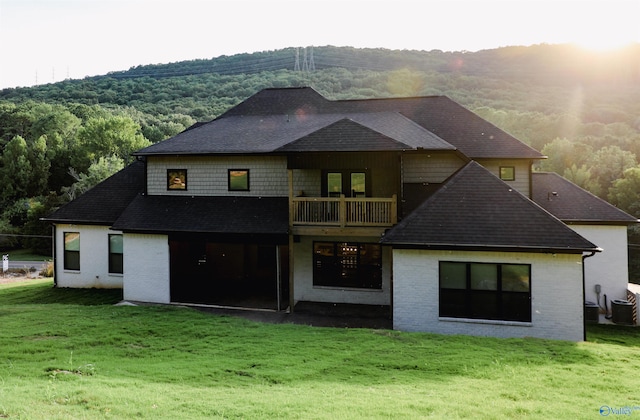 rear view of property featuring a balcony and a lawn