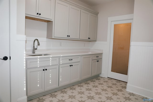 kitchen featuring light tile patterned flooring, sink, and white cabinets