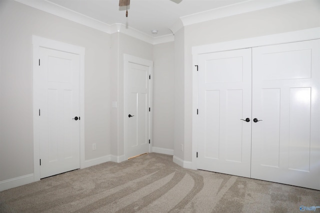 unfurnished bedroom with ceiling fan, crown molding, a closet, and light colored carpet